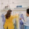 Two women browsing clothing in a stylish boutique, exploring various fashion options.