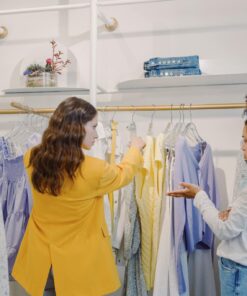 Two women browsing clothing in a stylish boutique, exploring various fashion options.