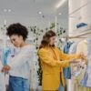 Two women shopping in a trendy clothing store, browsing stylish outfits.