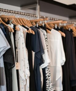 Vibrant clothing display on wooden hangers in a modern boutique setting.